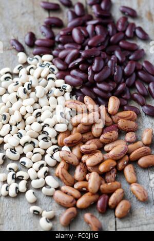 Rote Kidney-Bohnen, schwarze Augen Bohnen und Pinto Bohnen auf einem Holztisch Stockfoto