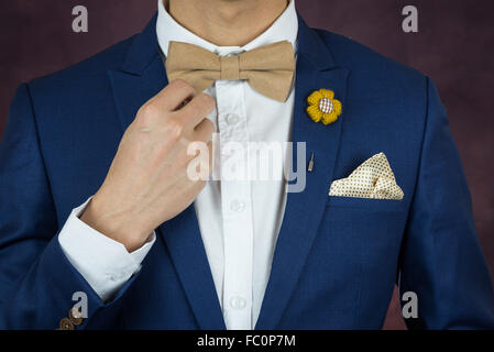 Mann im blauen Anzug mit Kaffee Creme Bowtie Farbe, Blumenbrosche und Dot Muster Taschentuch, Nähe einstellen, Fliege Stockfoto