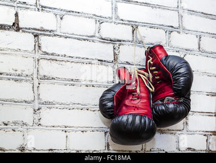 Ein paar der alten Boxhandschuhe hängen weiße Ziegel Wand Hintergrund. Stockfoto