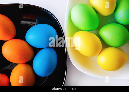 Bunte Ostereier auf schwarzen und weißen Platten. Ostern-Hintergrund. Ansicht von oben. Stockfoto