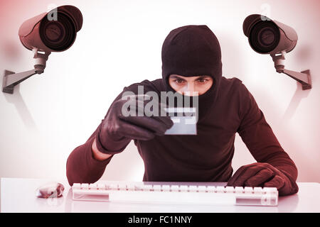 Zusammengesetztes Bild der Einbrecher machen Online-shopping mit Laptop und Kreditkarte Stockfoto
