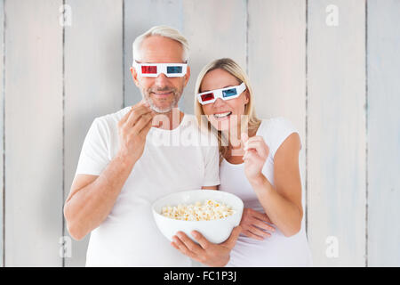 Zusammengesetztes Bild des glücklichen Paares mit 3d Brille Essen popcorn Stockfoto