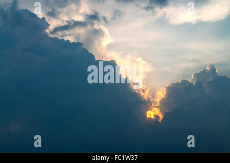 Die Sonne ist versteckt sich hinter der dunklen Wolke Hugh aber die hellen Lichtstrahl durch eine Ecke senden, als ob es ist Feuer in der s Stockfoto
