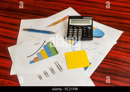 Haufen von gedruckten Diagrammen und Grafiken mit Taschenrechner, Büroklammern, gelbe Notiz und Stift auf Sie Stockfoto