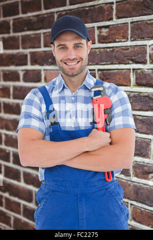 Zusammengesetztes Bild überzeugt junge männliche Mechaniker mit verstellbaren Schraubenschlüssel Stockfoto