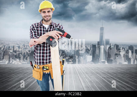 Zusammengesetztes Bild zuversichtlich männlichen Schreinerei mit Bohrmaschine und Planke Stockfoto