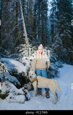 Frau mit Hund im Winterwald spazieren Stockfoto