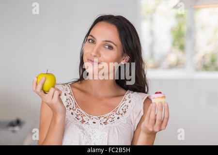 Schöne Brünette mit Mini Cupcake und ein Apfel Stockfoto