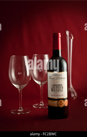 Eine Flasche Bordeaux erwartet zwei Personen, eventuell mit einer langen stemmed roten Rose zu trinken. Stockfoto