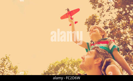 Junge mit Spielzeug Flugzeug sitzen auf den Schultern der Väter Stockfoto