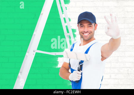 Zusammengesetztes Bild glücklich Handwerker mit Farbe Walze gestikulieren okay Stockfoto