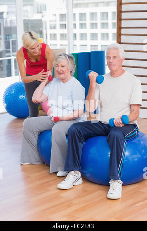 Trainer motivieren älteres Paar beim Heben der Hanteln Stockfoto