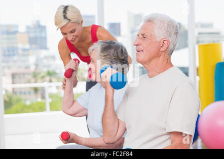 Senior woman Aufhebung Hanteln beim Trainer unterstützen Frau im Fitnessstudio Stockfoto