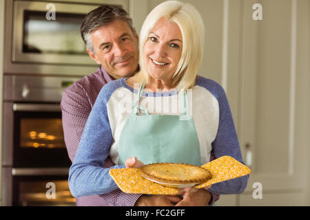 Reife Blondine hält frische Torte mit Mann umarmt Ihr Stockfoto