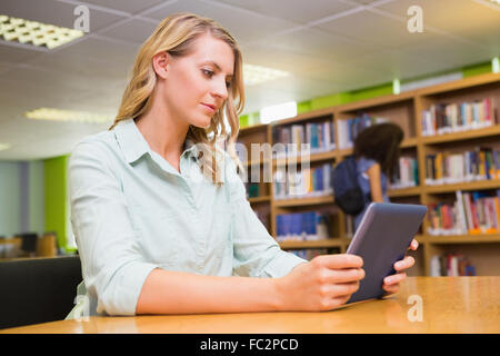 Hübsche Studentin Studium in der Bibliothek mit tablet Stockfoto