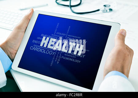 Nahaufnahme von einem Arzt Mann sitzt an seinem Schreibtisch einen Tablet-Computer mit eine Tag-Cloud über Gesundheit in seinem Bildschirm halten Stockfoto