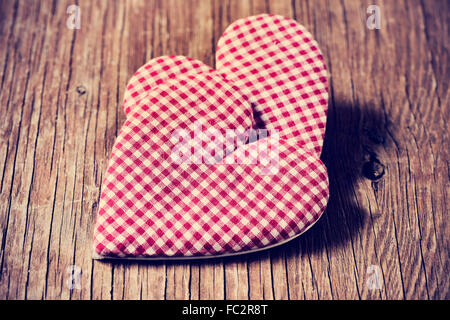 zwei rot-weiß karierte Herzen auf eine rustikale Holzoberfläche Stockfoto