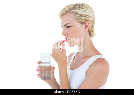 Hübsche blonde Frau mit Glas Wasser und bereit, die rote Pille schlucken Stockfoto