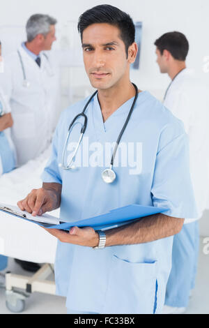 Bericht lesen, mit Kollegen und Patienten hinter Stockfoto