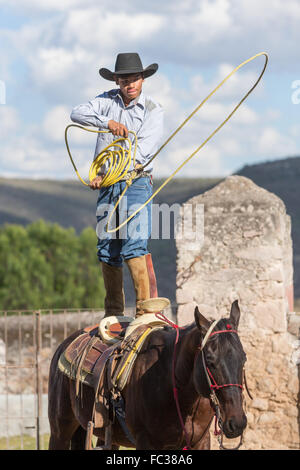 Eine mexikanische Charro oder Cowboy Praktiken Abseilen Fähigkeiten stehen auf seinem Pferd vor einem Charreada Wettkampf auf einer Hacienda-Ranch in Alcocer, Mexiko. Die Charreada ist eine traditionelle mexikanische Rodeo und testet die Fähigkeiten des Cowboys reiten, Abseilen und Vieh zu kontrollieren. Stockfoto