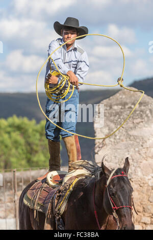 Eine mexikanische Charro oder Cowboy Praktiken Abseilen Fähigkeiten stehen auf seinem Pferd vor einem Charreada Wettkampf auf einer Hacienda-Ranch in Alcocer, Mexiko. Die Charreada ist eine traditionelle mexikanische Rodeo und testet die Fähigkeiten des Cowboys reiten, Abseilen und Vieh zu kontrollieren. Stockfoto