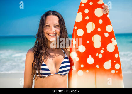 Hübsche Brünette mit einem Surfbrett an einem sonnigen Tag Stockfoto