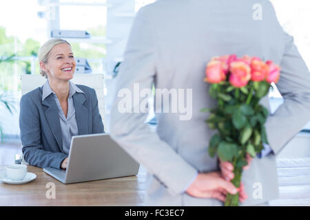 Geschäftsmann versteckt Blumen hinter Rücken für Kollegen Stockfoto