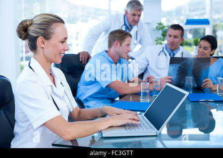 Schönes Lächeln auf den Lippen Arzt Tippen auf Tastatur mit ihrem Team hinter Stockfoto