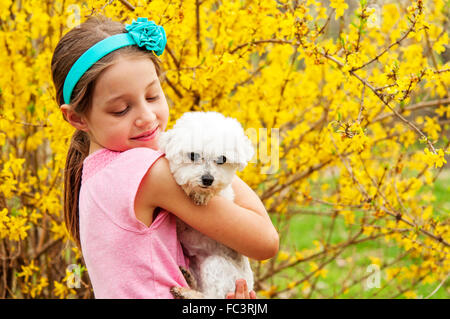 Mädchen mit ihrem Hund von Forsythien bush Stockfoto