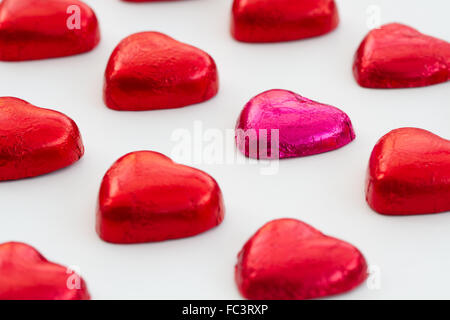 Zum Valentinstag, herzförmige Pralinen und Bonbons auf einem weißen, isolierten Hintergrund. Süßigkeiten aus ordentlich in Reihen und Zeilen festgelegt. Stockfoto