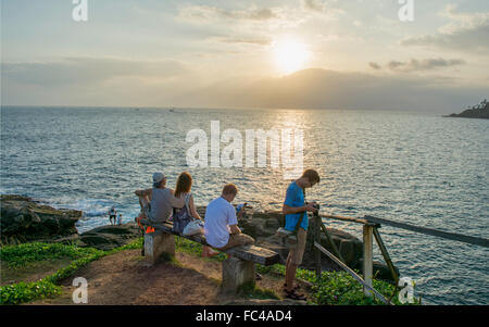 Reisende warten auf eine Bank auf einer Klippe mit einem Schuss den Sonnenuntergang in Mirrissa, Sri Lanka zu übernehmen. Stockfoto