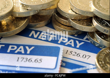 LOHNZETTEL ZEIGT NETTO ZU ZAHLEN, MIT EINEM PFUND-MÜNZEN WIEDER LOHN GEHALT ARBEITNEHMER EINKOMMEN EINKOMMEN HAUSHALTSBUDGET JOB JOBS UK Stockfoto