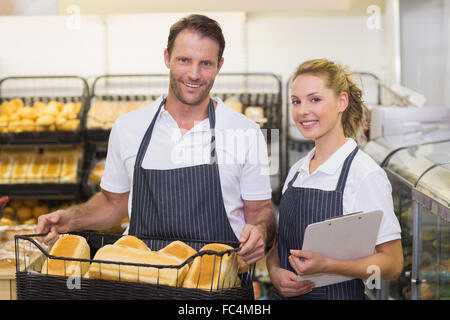 Porträt einer lächelnden Bäcker Holding einen Korb mit Brot und Notizblock Stockfoto