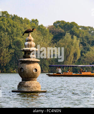 Vogel ruht auf eine geschnitzte Statue in West Lake, einem Süßwassersee in Hangzhou, der Hauptstadt der Provinz Zhejiang im Osten Chinas. Stockfoto