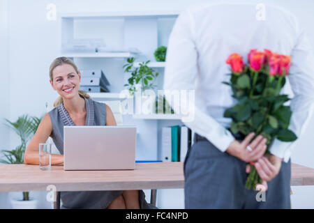 Geschäftsmann versteckt Blumen hinter Rücken für Kollegen Stockfoto