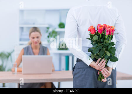 Geschäftsmann versteckt Blumen hinter Rücken für Kollegen Stockfoto