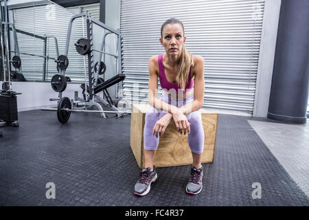 Schwere muskulöse Frau sitzen auf einer Holzkiste Stockfoto