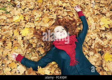 rothaarige Mädchen liegen auf Blätter im Stadtpark, Herbst-Saison Stockfoto