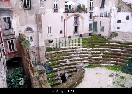 Neapel, Italien. Das römische Theater von Neapolis umgeben von den Häusern, ist eine archäologische Stätte, die im Herzen des historischen Zentrum von Neapel, in der Decumano Maggiore befindet. Die Website befindet sich gerade in dem Bereich zwischen über Altware.  Ein Teil des Theaters ist die letzte Phase der Reise mit der u-Bahn von Neapel, während andere Fragmente entlang der Decumani frei sichtbar sind. Die Häuser wurden auf den Ruinen des antiken römischen Theaters gebaut. Stockfoto