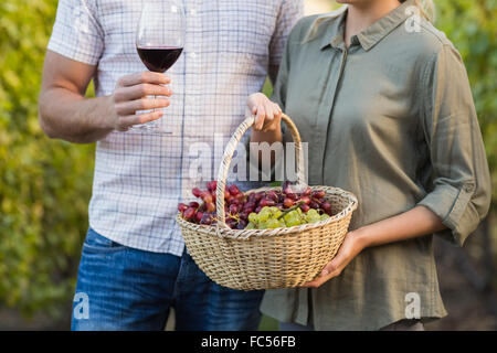 Zwei junge glücklich Winzer hält einen Korb mit Trauben und einem Glas Wein Stockfoto