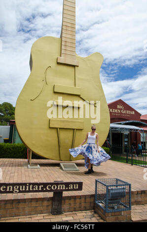 Glückliche Mädchen tanzen vor der großen Gitarre bei Tamworth NSW Australia Stockfoto