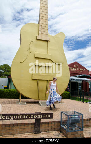 Glückliche Mädchen tanzen vor der großen Gitarre bei Tamworth NSW Australia Stockfoto