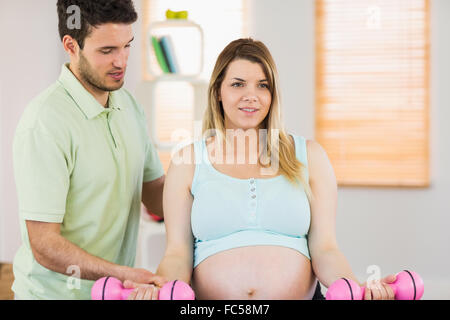 Schwangere Frau auf Gymnastikball Hanteln heben Stockfoto