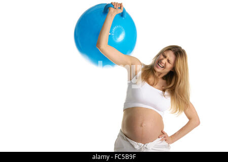 Müde schwangere Frau holt große blaue Kugel Stockfoto