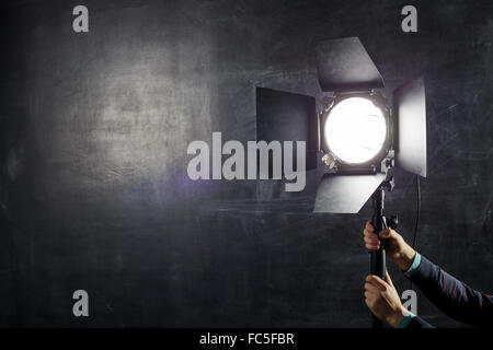 Fotograf stellt Beleuchtung Ausrüstung auf einem Hintergrund von Tafel Stockfoto