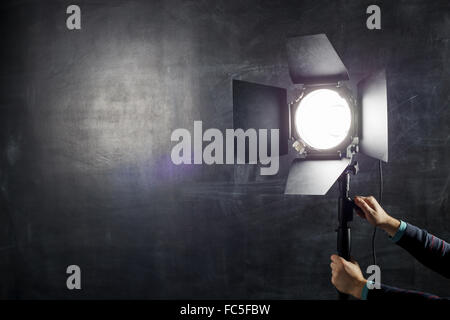 Fotograf stellt Beleuchtung Ausrüstung auf einem Hintergrund von Tafel Stockfoto