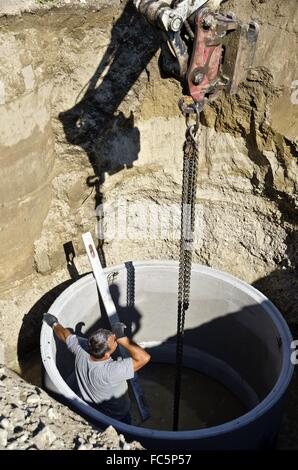 Grube mit Arbeiter in einem konkreten Schacht Stockfoto