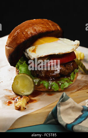 Burger mit Ei auf einem Holzbrett Stockfoto