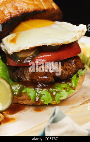 Burger mit Ei auf einem Holzbrett closeup Stockfoto