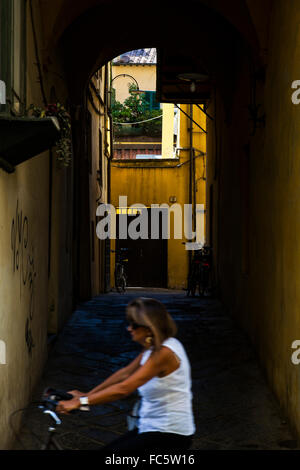 Frau Rad vorbei an einem Torbogen in Lucca, Toskana, Italien Stockfoto